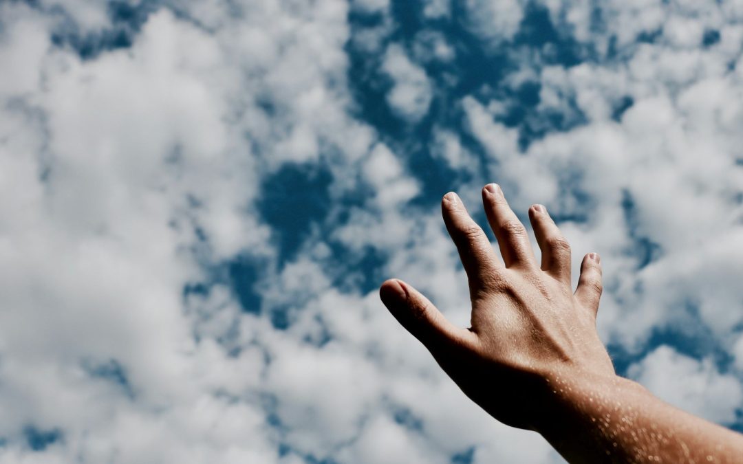 a photo of a man reaching out to the sky